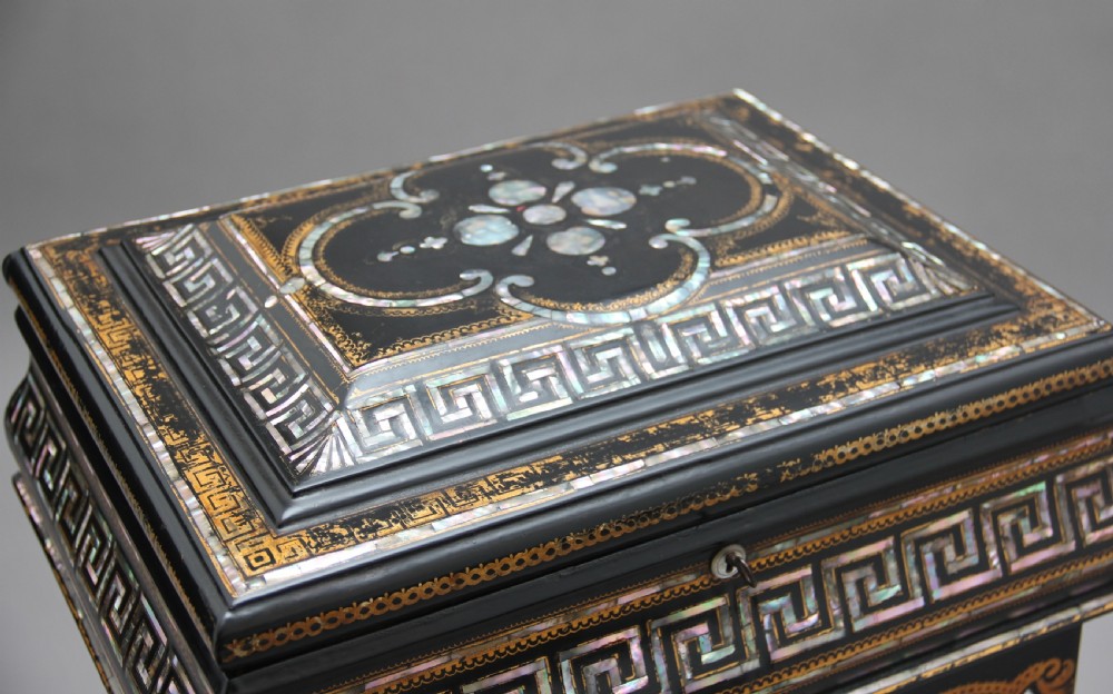 A nineteenth-century black lacquered papier-mache work table featuring mother-of-pearl Greek key inlay, hand-gilded detailing, a hinged box top, and a pedestal base on castors. View XII