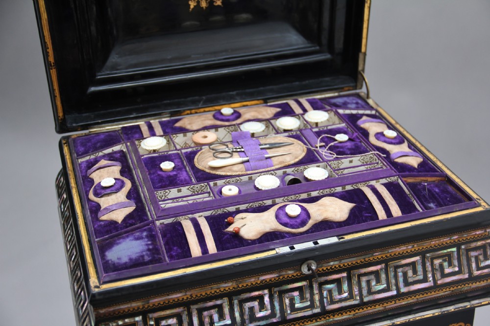 A nineteenth-century black lacquered papier-mache work table featuring mother-of-pearl Greek key inlay, hand-gilded detailing, a hinged box top, and a pedestal base on castors. View XIV