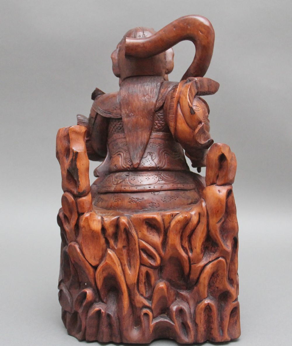 A 19th-century Chinese hand-carved wooden figure depicting a bearded warrior deity in armour standing over a serpent and tortoise. View IV