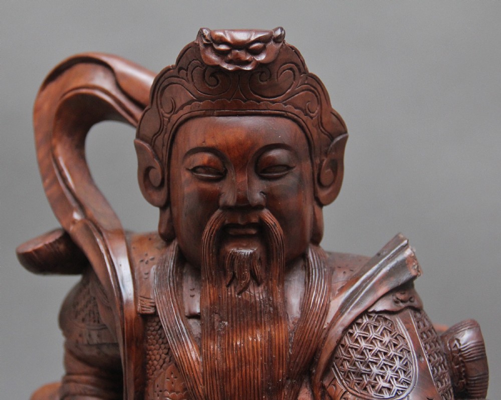 A 19th-century Chinese hand-carved wooden figure depicting a bearded warrior deity in armour standing over a serpent and tortoise. View VI