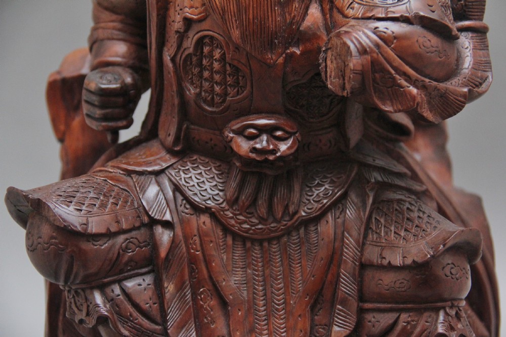 A 19th-century Chinese hand-carved wooden figure depicting a bearded warrior deity in armour standing over a serpent and tortoise. View VII
