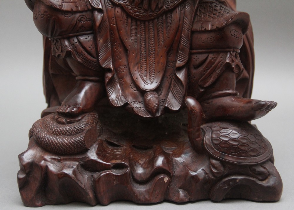 A 19th-century Chinese hand-carved wooden figure depicting a bearded warrior deity in armour standing over a serpent and tortoise. View VIII