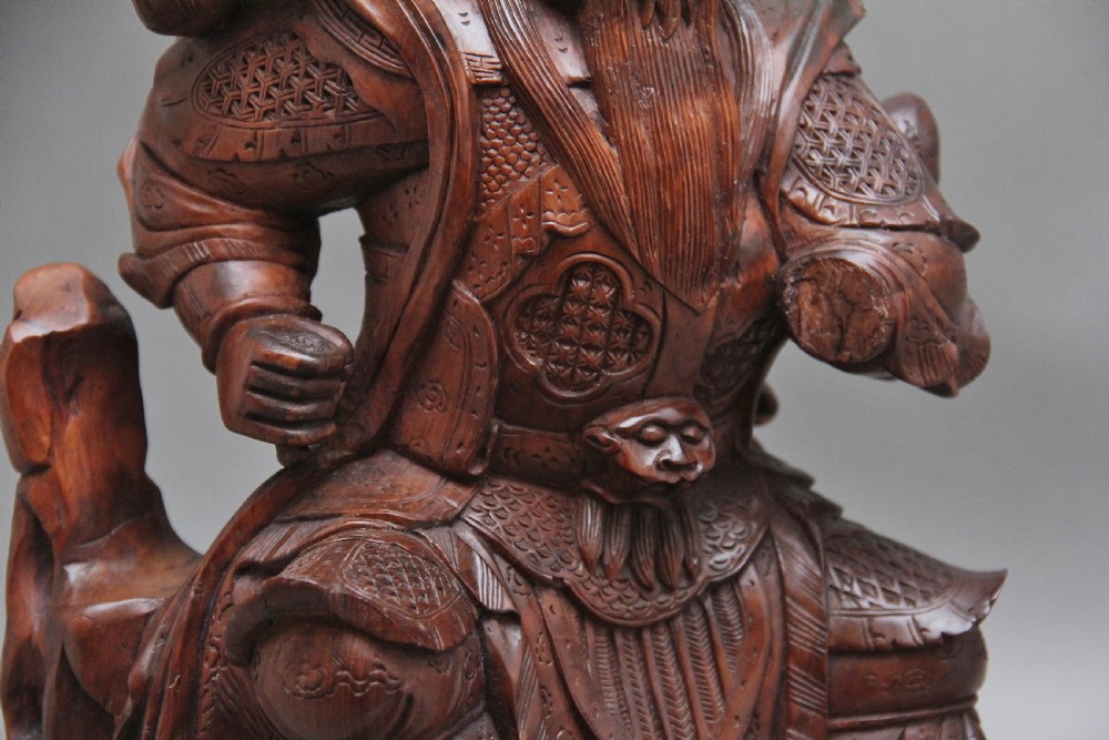 A 19th-century Chinese hand-carved wooden figure depicting a bearded warrior deity in armour standing over a serpent and tortoise. View IX
