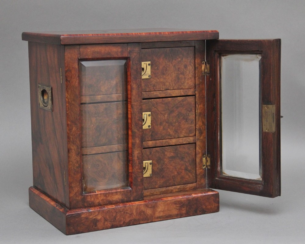 A 19th-century burr walnut tabletop cabinet with an open glazed door showing interior drawers with brass flush handles.
