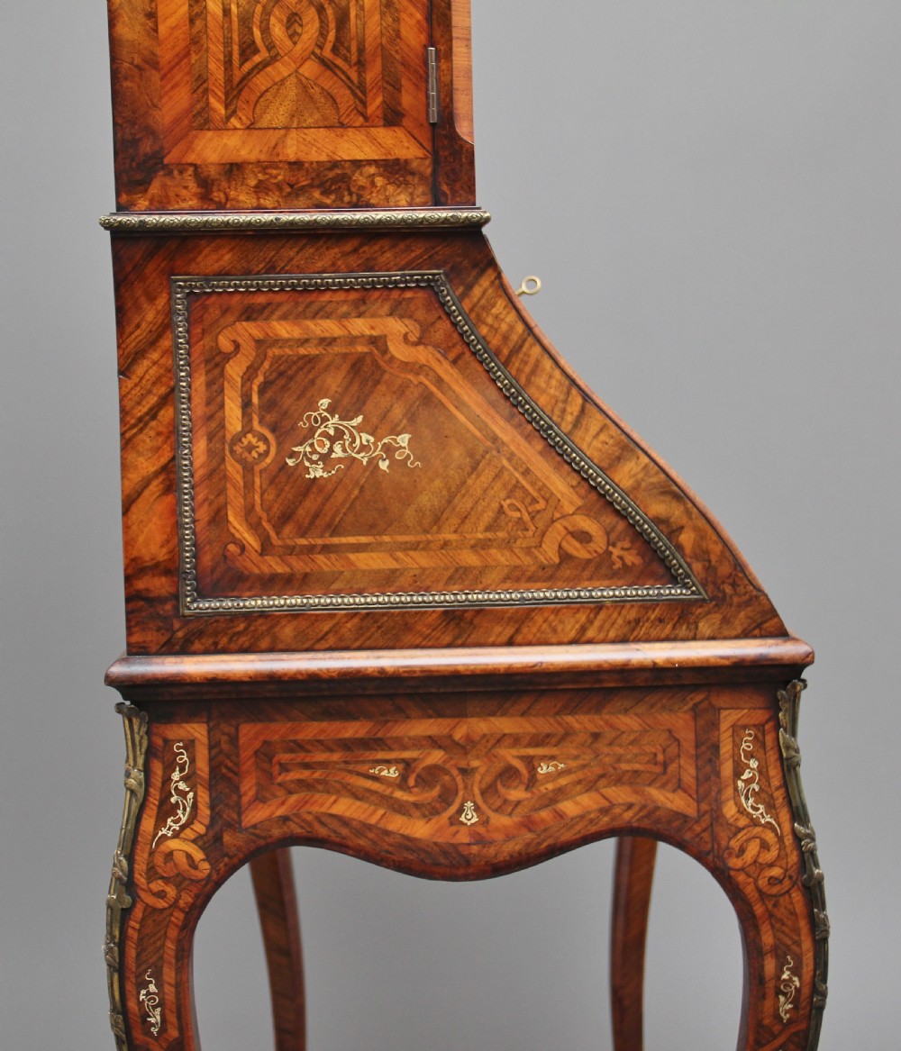 A nineteenth-century French walnut and kingwood bureau de dame with floral marquetry inlay, brass mounts, cabriole legs, and an upper cabinet with mirrored doors. View V
