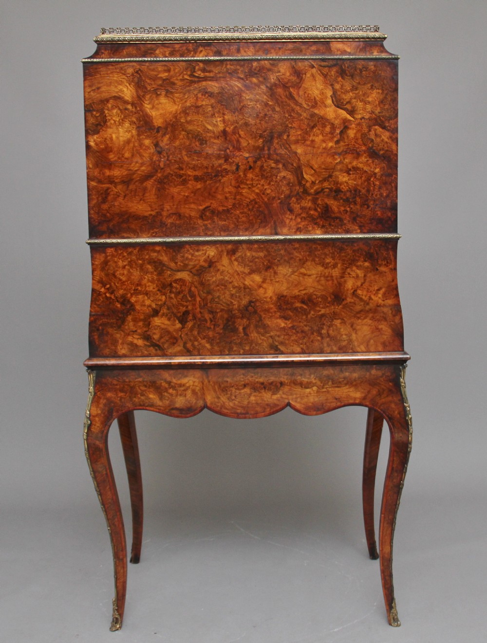 A nineteenth-century French walnut and kingwood bureau de dame with floral marquetry inlay, brass mounts, cabriole legs, and an upper cabinet with mirrored doors. View VI