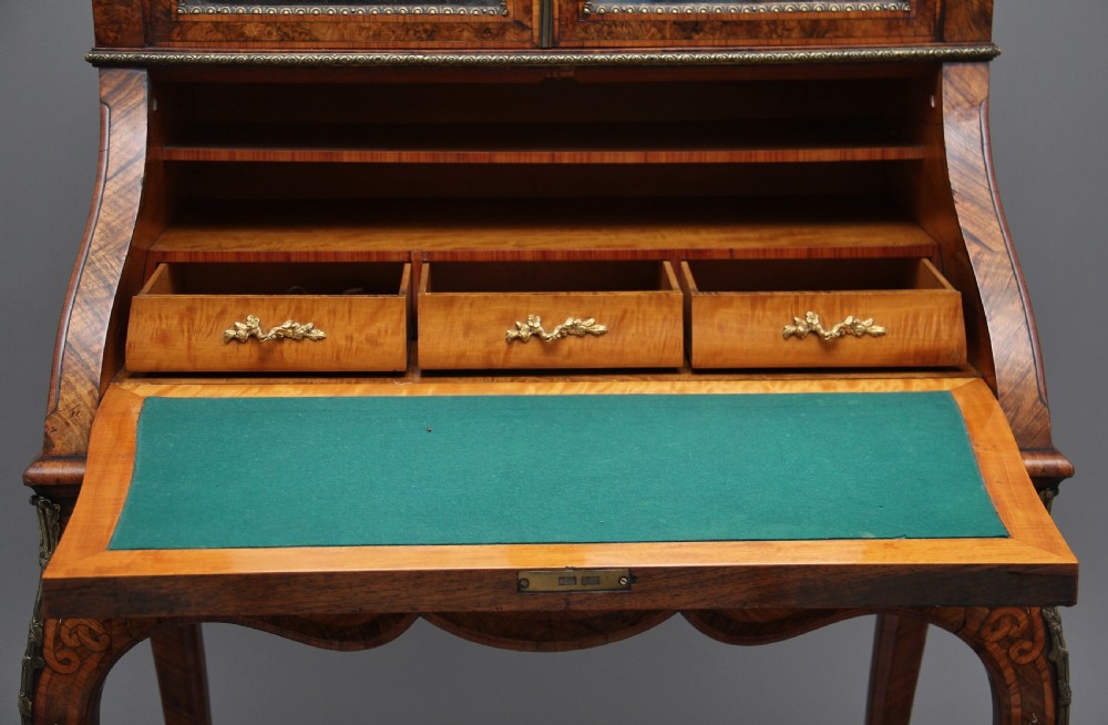 A nineteenth-century French walnut and kingwood bureau de dame with floral marquetry inlay, brass mounts, cabriole legs, and an upper cabinet with mirrored doors. View XIV