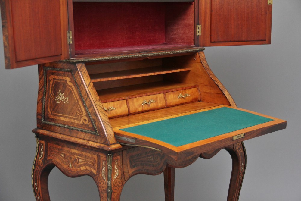 A nineteenth-century French walnut and kingwood bureau de dame with floral marquetry inlay, brass mounts, cabriole legs, and an upper cabinet with mirrored doors. View XV