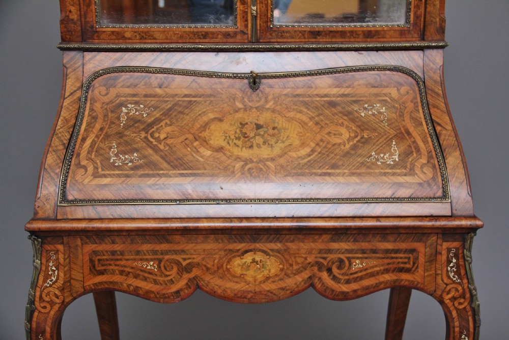 A nineteenth-century French walnut and kingwood bureau de dame with floral marquetry inlay, brass mounts, cabriole legs, and an upper cabinet with mirrored doors. View XXII