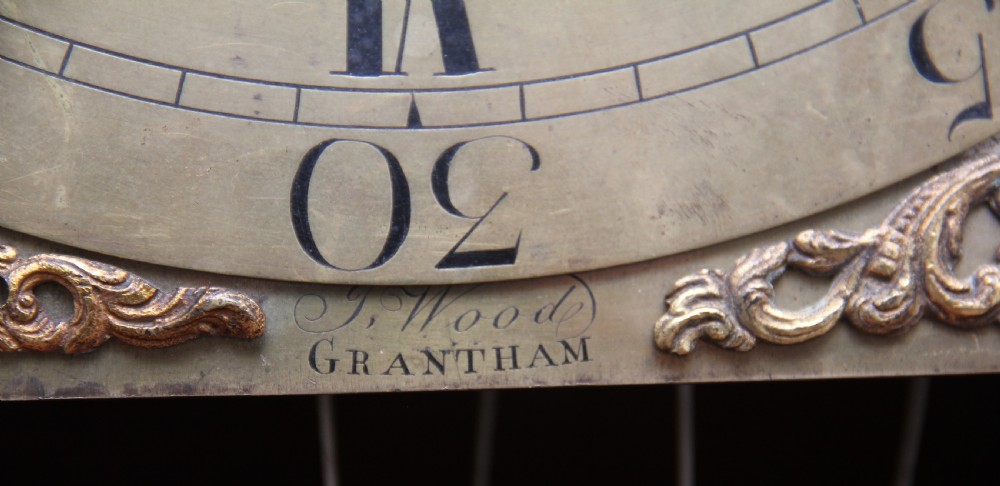 An 18th-century Georgian flame mahogany longcase clock featuring an arched hood, brass dial with moon phase display, and polished wood casing. View VIII