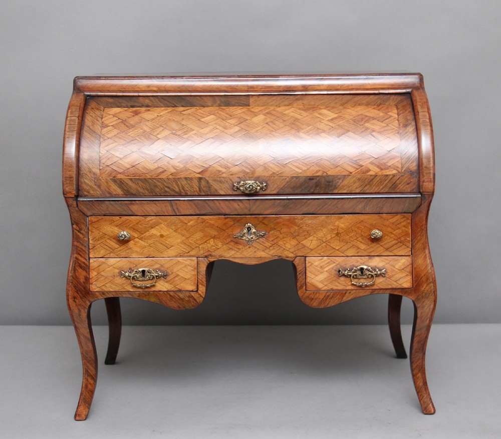A 19th-century miniature walnut desk with geometric parquetry pattern, a cylinder roll top, cabriole legs, and brass handles.