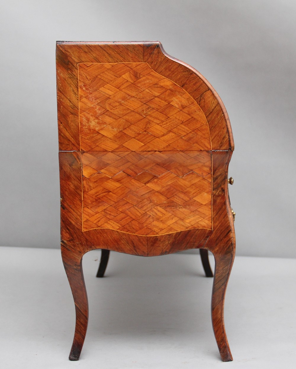 A 19th-century miniature walnut desk with geometric parquetry pattern, a cylinder roll top, cabriole legs, and brass handles. View V