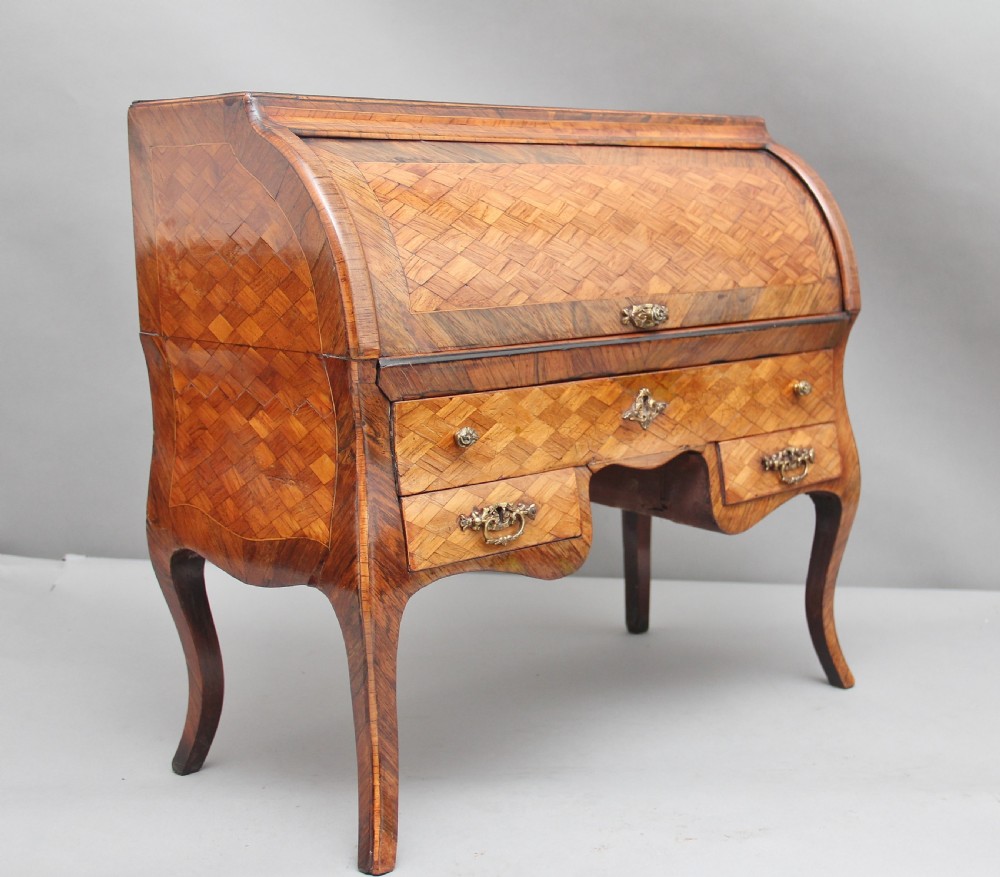 A 19th-century miniature walnut desk with geometric parquetry pattern, a cylinder roll top, cabriole legs, and brass handles. View VIII