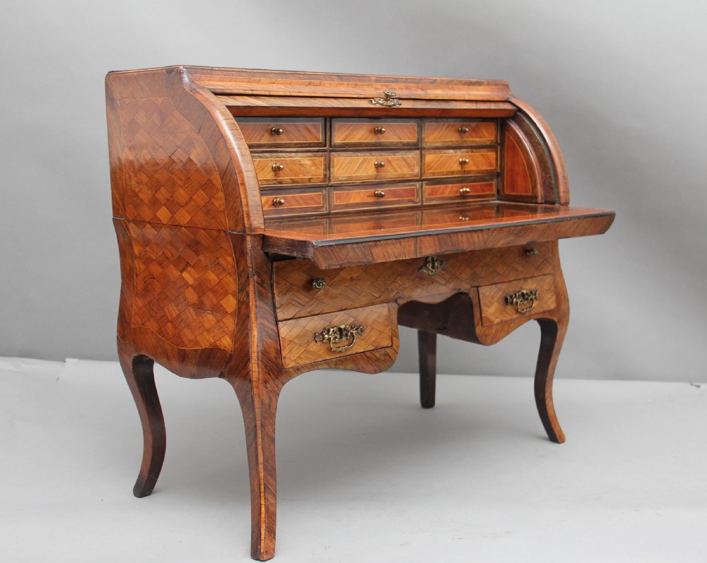 A 19th-century miniature walnut desk with geometric parquetry pattern, a cylinder roll top, cabriole legs, and brass handles. View IX