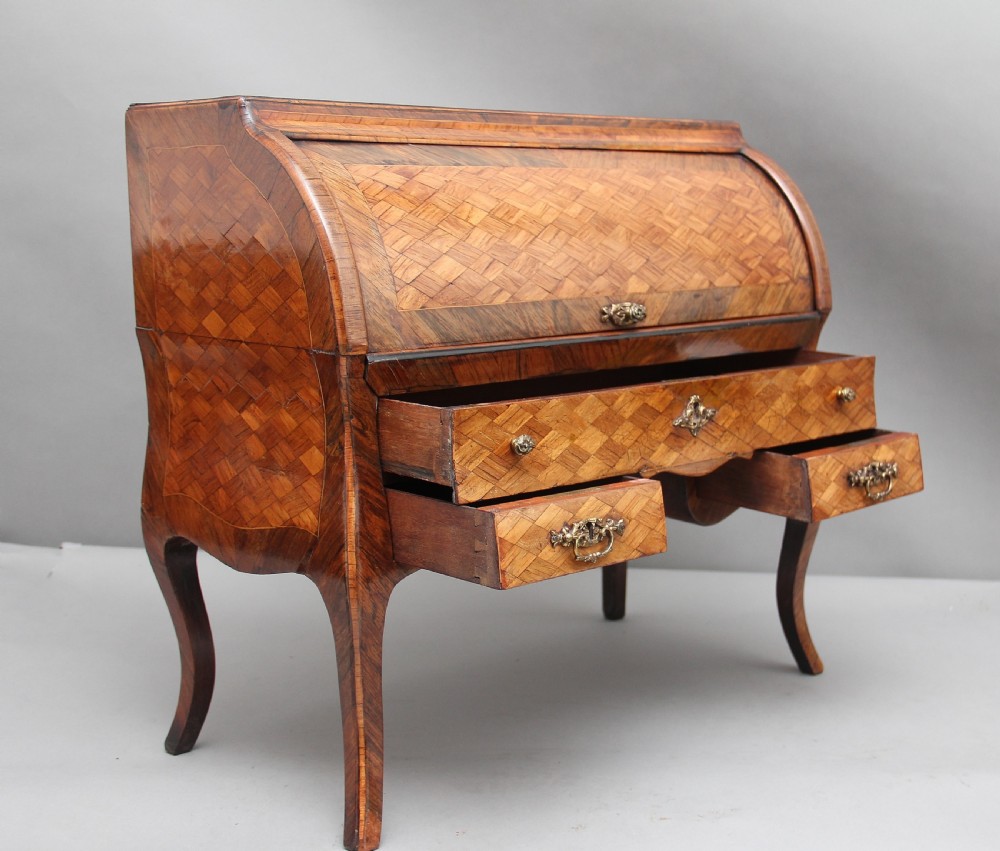 A 19th-century miniature walnut desk with geometric parquetry pattern, a cylinder roll top, cabriole legs, and brass handles. View X