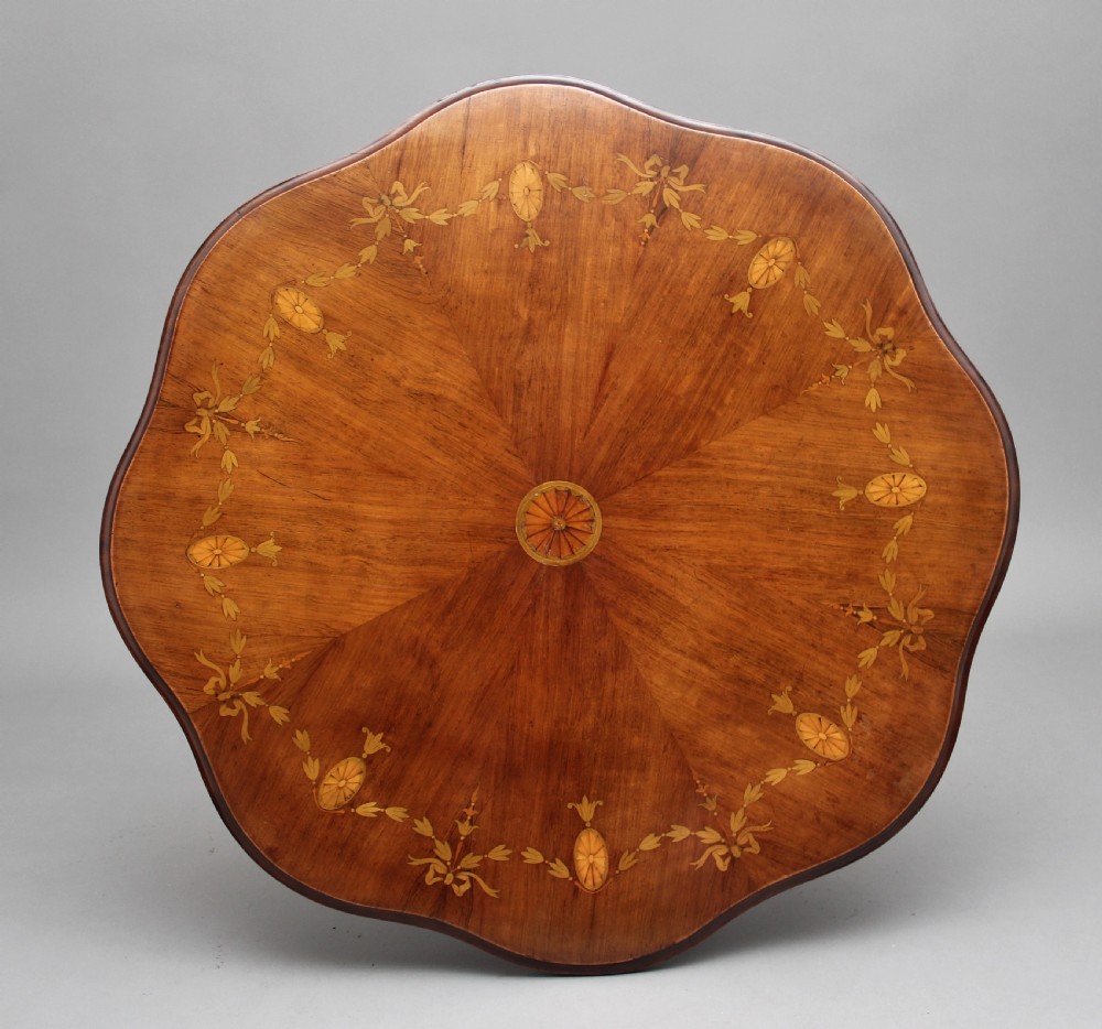 A 19th-century rosewood centre table with a serpentine-edged marquetry top, four fluted legs, an X-shaped stretcher, and brass castors. View III