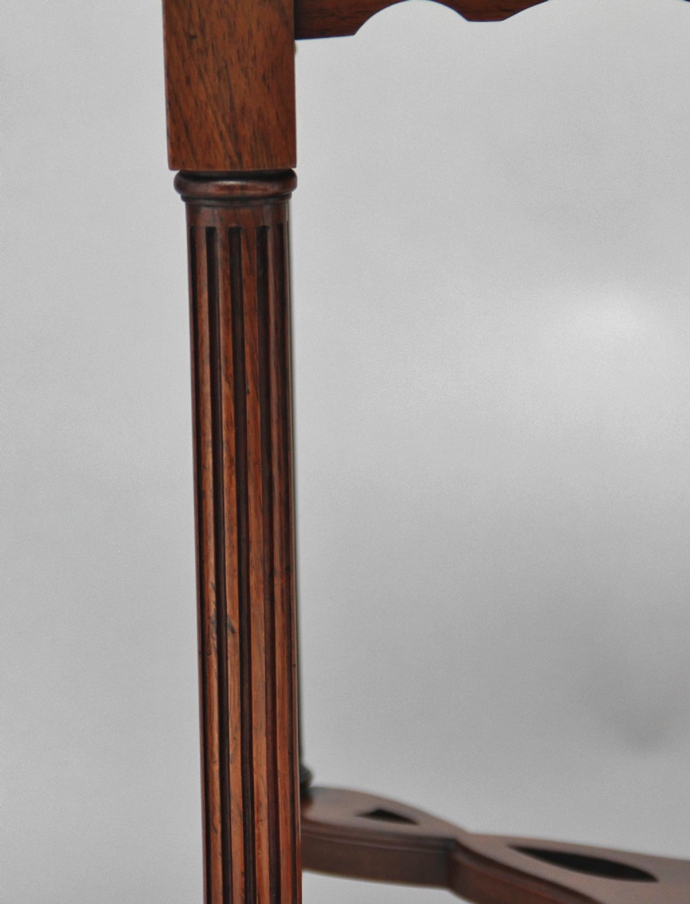 A 19th-century rosewood centre table with a serpentine-edged marquetry top, four fluted legs, an X-shaped stretcher, and brass castors. View VIII