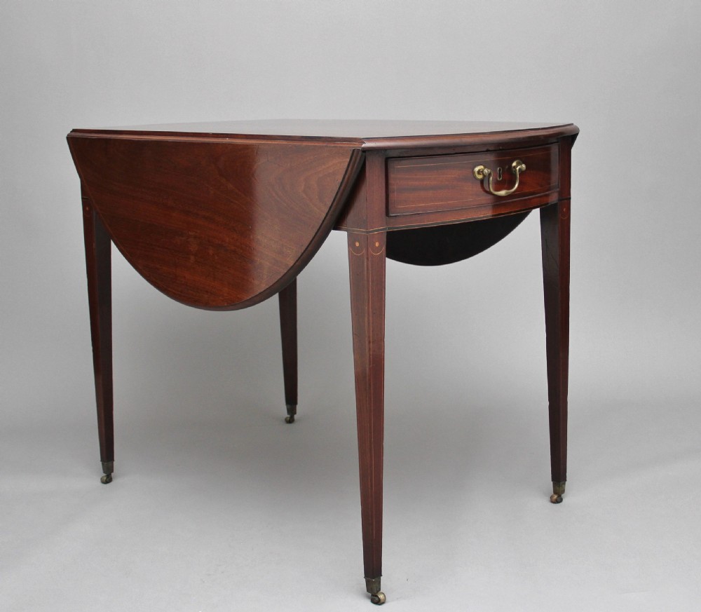 An 18th-century mahogany Pembroke table with two drop leaves, a single frieze drawer with a brass handle, boxwood stringing inlay, and square tapered legs on brass castors.