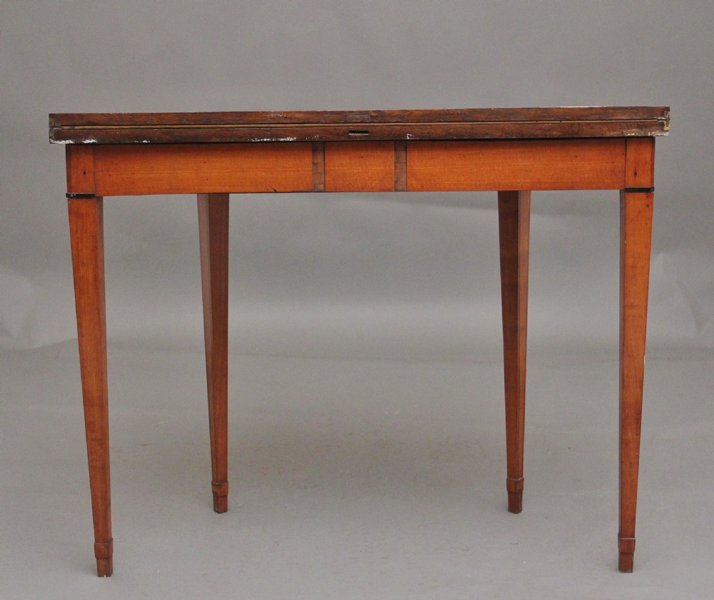 An early nineteenth-century demilune satinwood card table featuring hand-painted floral swags along the apron and slender tapered square legs. View VI