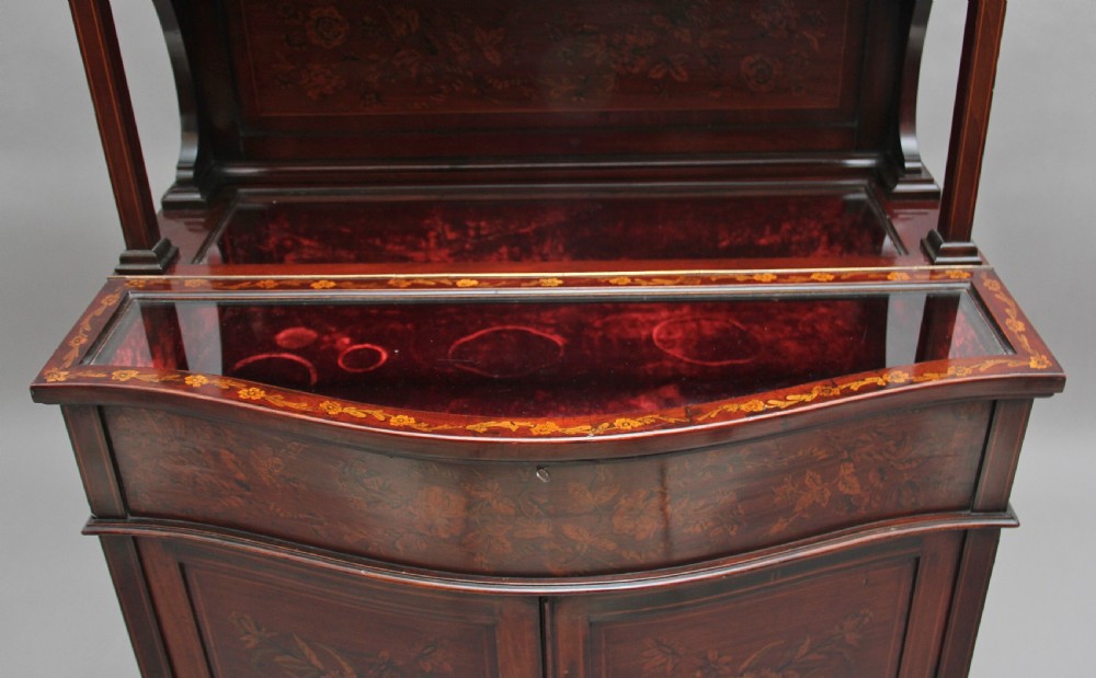 A 19th-century mahogany display cabinet featuring floral marquetry inlays, a glazed upper section with glass shelves, and a bow-front lower cabinet on tapered legs. View X