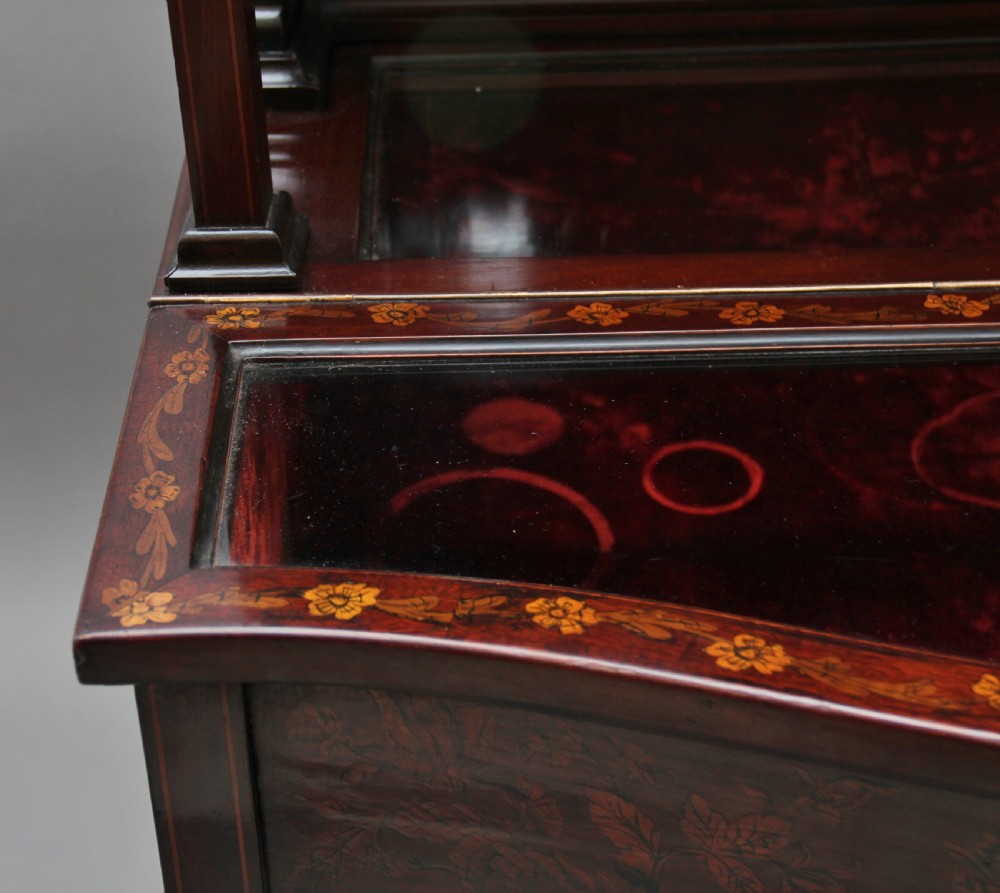 A 19th-century mahogany display cabinet featuring floral marquetry inlays, a glazed upper section with glass shelves, and a bow-front lower cabinet on tapered legs. View XII