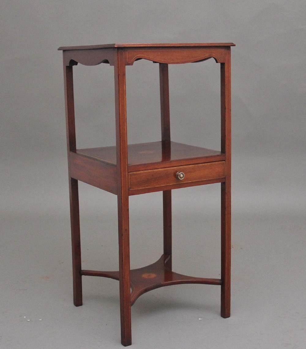 A tall, slender 19th-century mahogany bedside table featuring line inlay, a single drawer with a round brass knob, an open upper shelf tier, and an X-frame lower stretcher.