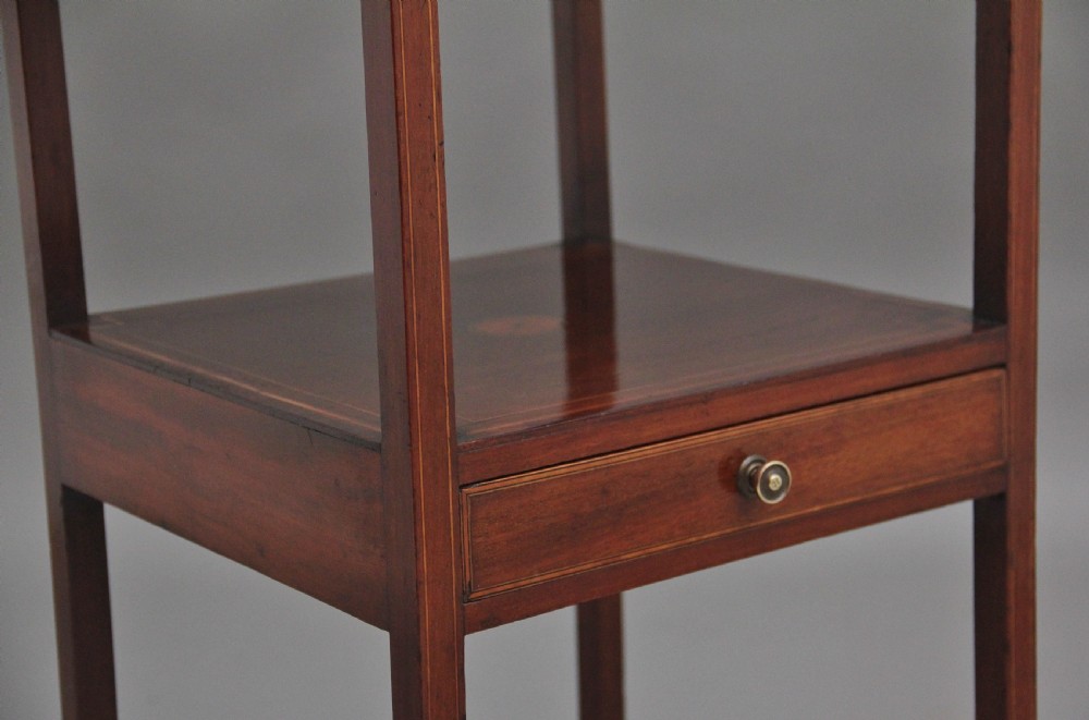 A tall, slender 19th-century mahogany bedside table featuring line inlay, a single drawer with a round brass knob, an open upper shelf tier, and an X-frame lower stretcher. View X