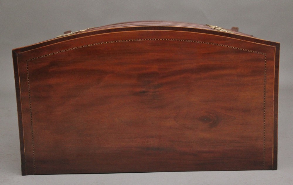 An 18th-century bowfront mahogany chest featuring four graduated drawers with oval brass ring handles, decorative inlay, and splayed bracket feet. View X