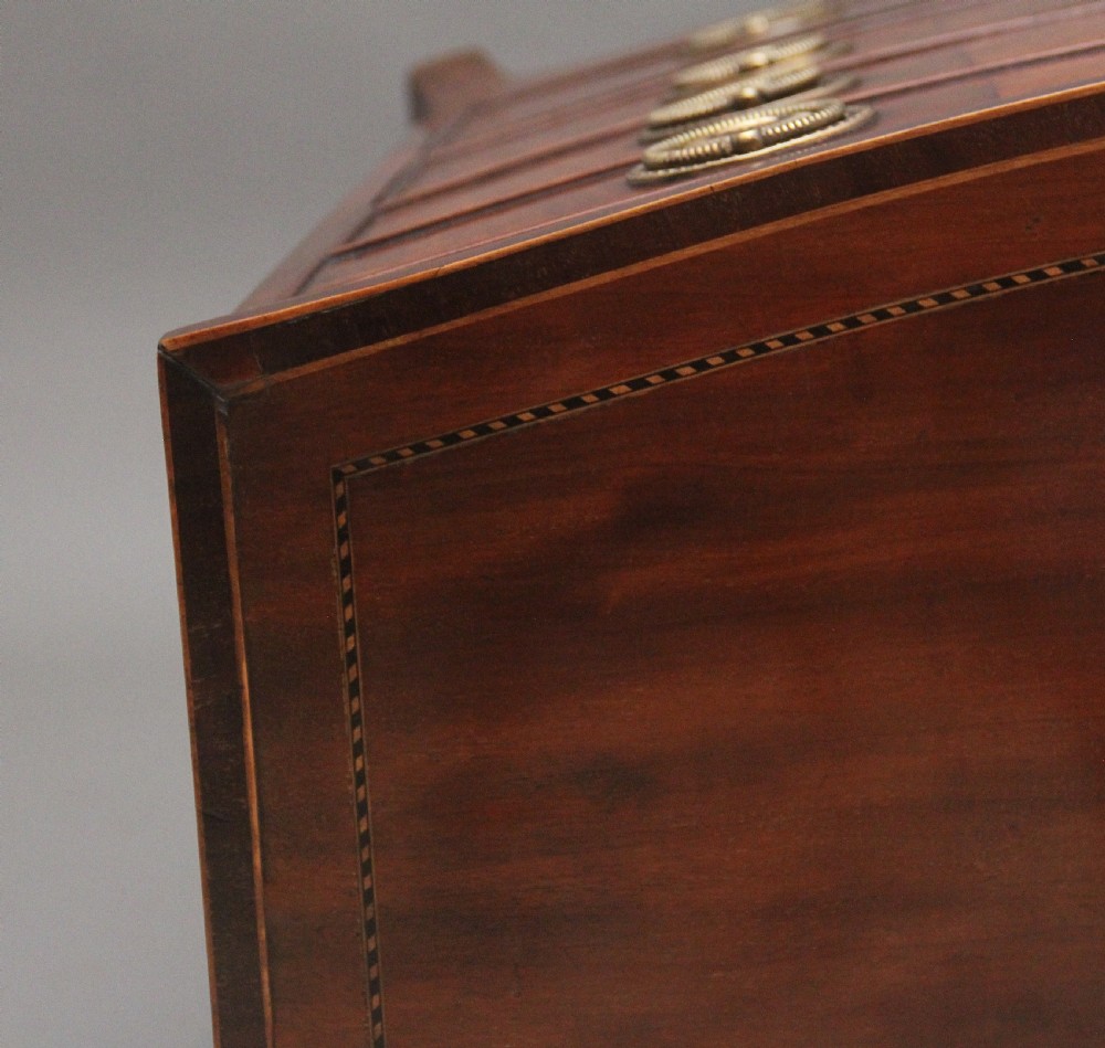 An 18th-century bowfront mahogany chest featuring four graduated drawers with oval brass ring handles, decorative inlay, and splayed bracket feet. View XI