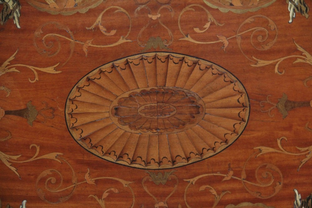 An oval 19th-century satinwood tray featuring detailed marquetry inlays of cherubs, foliate scrolls, a central sunburst medallion, and brass handles at each end. View III