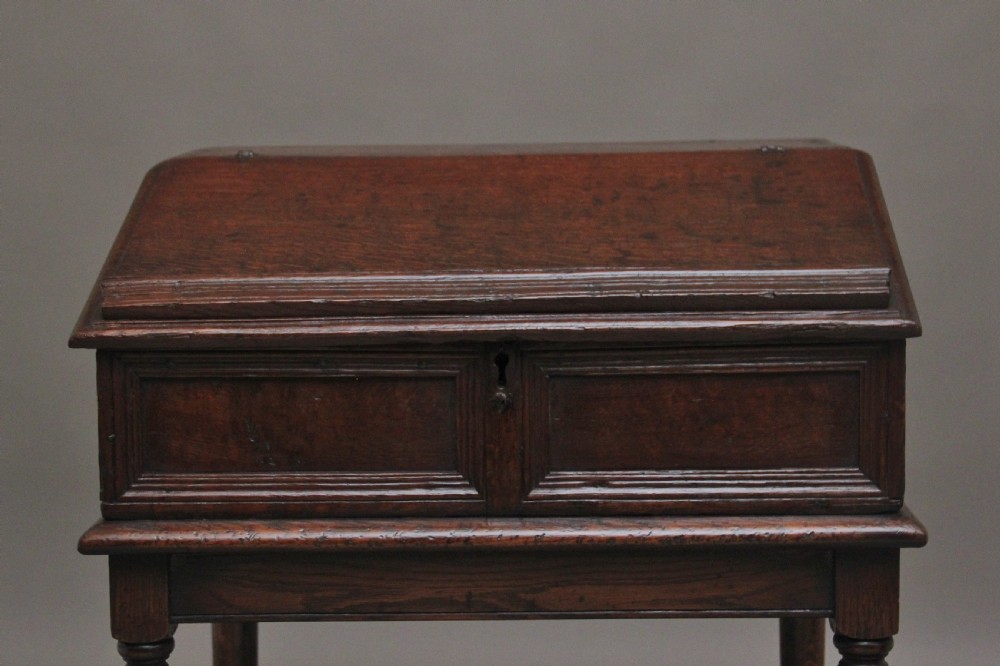 An 18th-century dark oak slope-front writing desk mounted on a stand with turned legs and lower stretchers. View IV