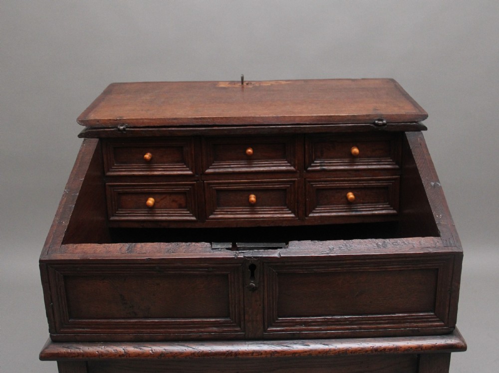 An 18th-century dark oak slope-front writing desk mounted on a stand with turned legs and lower stretchers. View V
