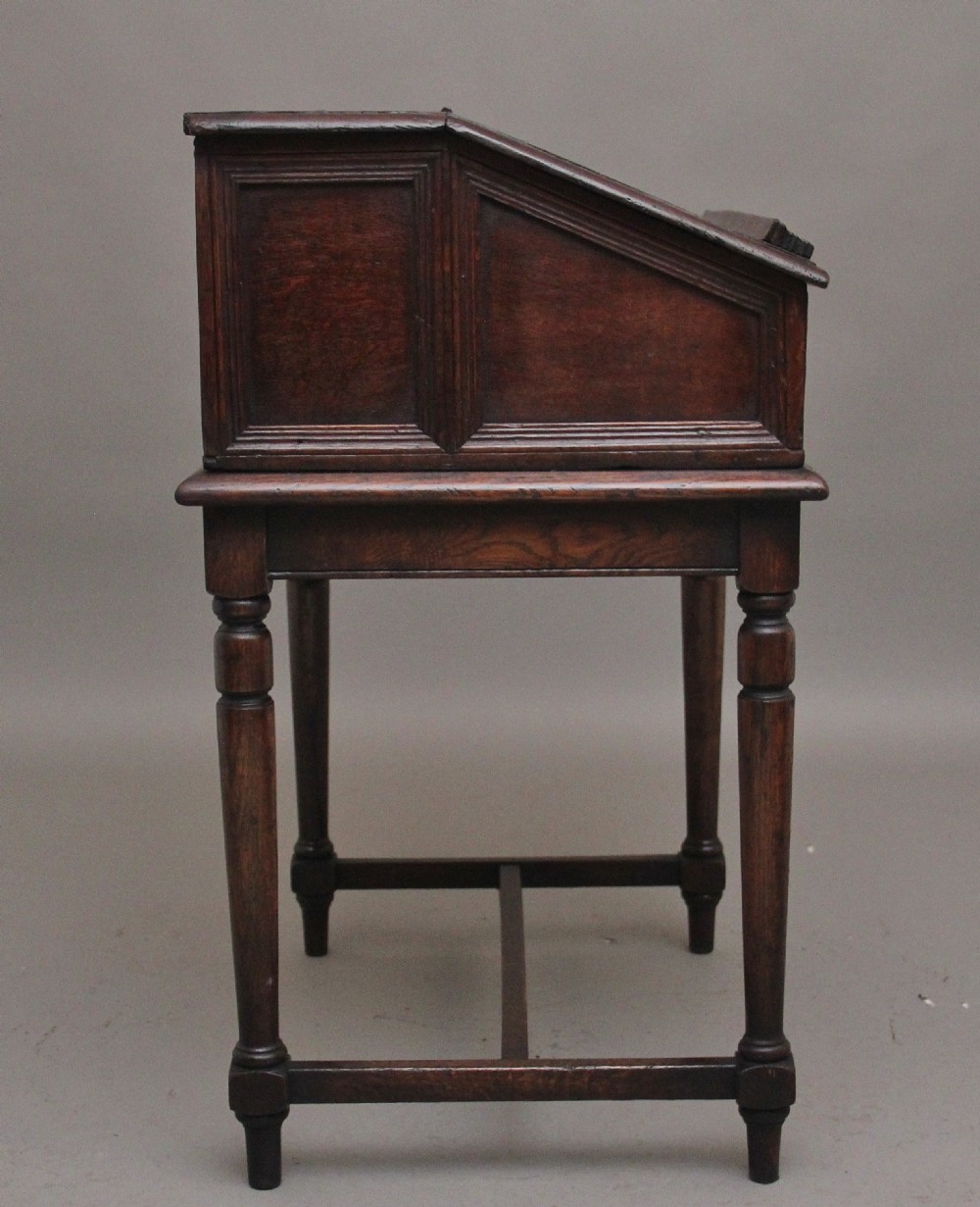 An 18th-century dark oak slope-front writing desk mounted on a stand with turned legs and lower stretchers. View VII
