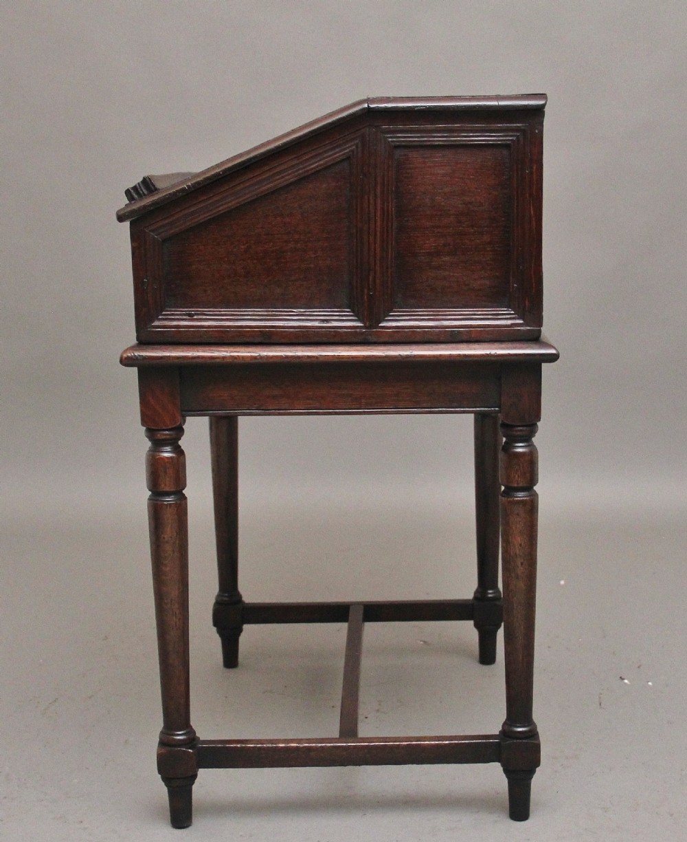An 18th-century dark oak slope-front writing desk mounted on a stand with turned legs and lower stretchers. View IX