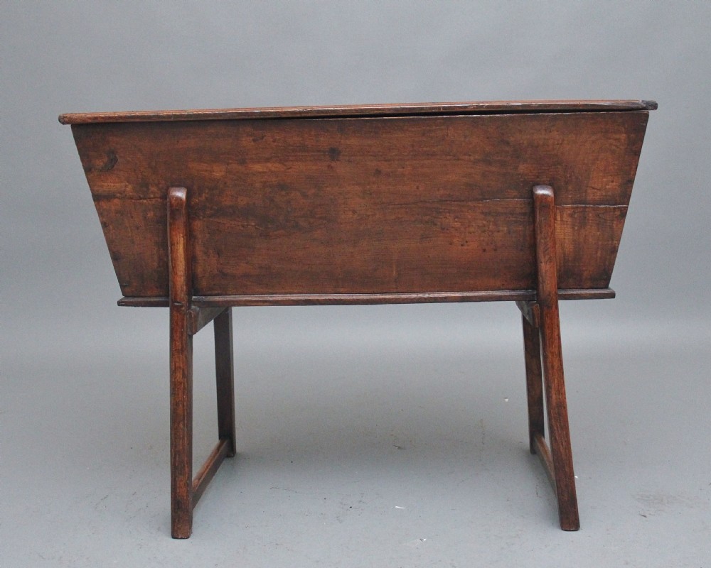 An 18th-century elm dough bin with a flat rectangular lid resting on a four-legged timber stand. View IV