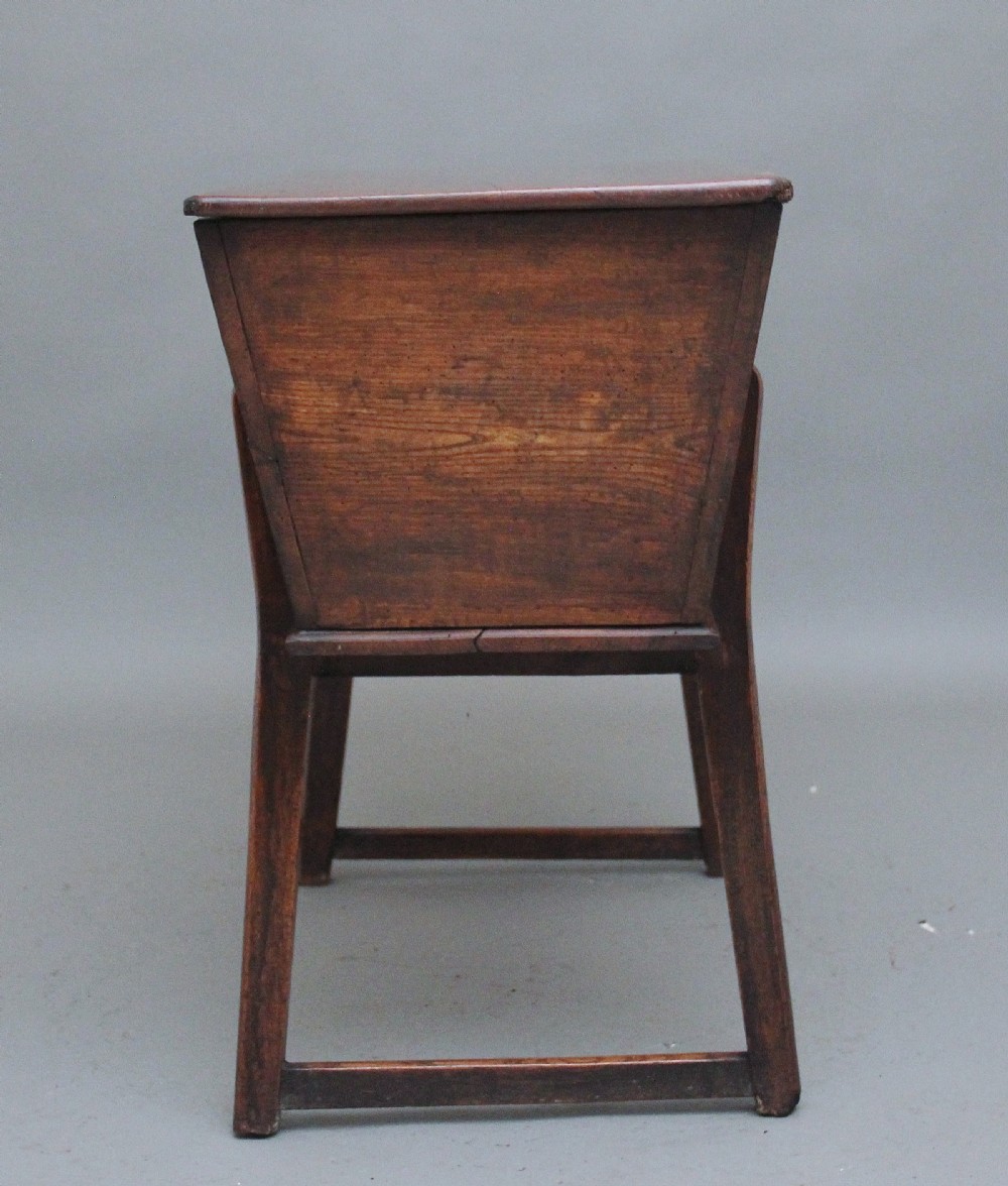 An 18th-century elm dough bin with a flat rectangular lid resting on a four-legged timber stand. View V