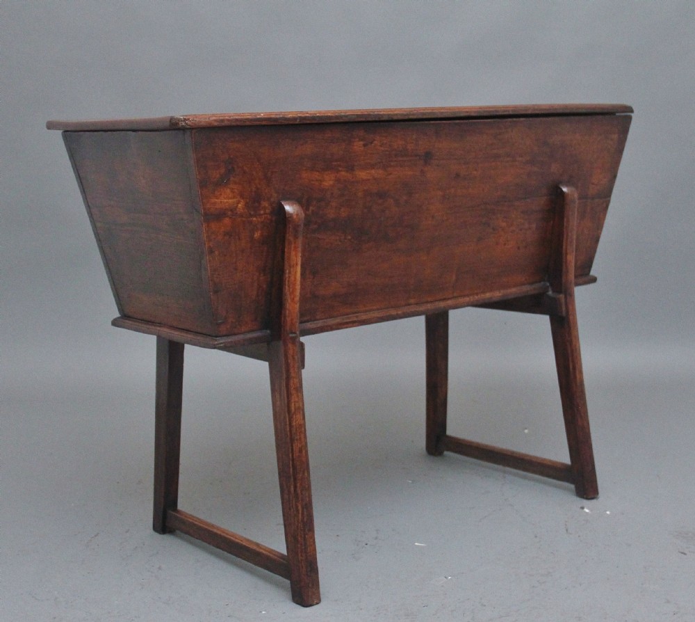 An 18th-century elm dough bin with a flat rectangular lid resting on a four-legged timber stand. View VII