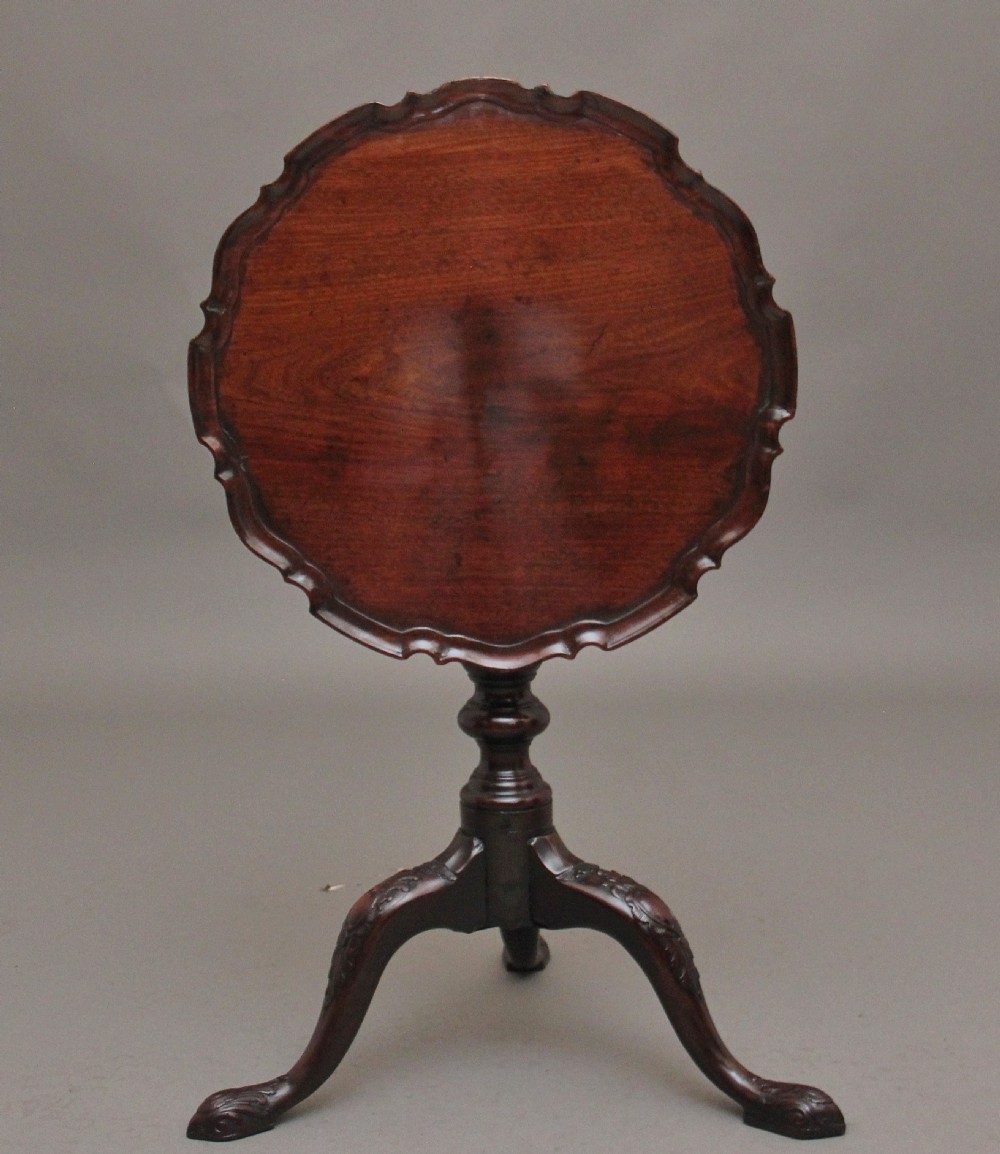 An 18th-century dark mahogany tripod table with a carved scalloped edge shown with its top tilted vertically on a turned pedestal stem. View V