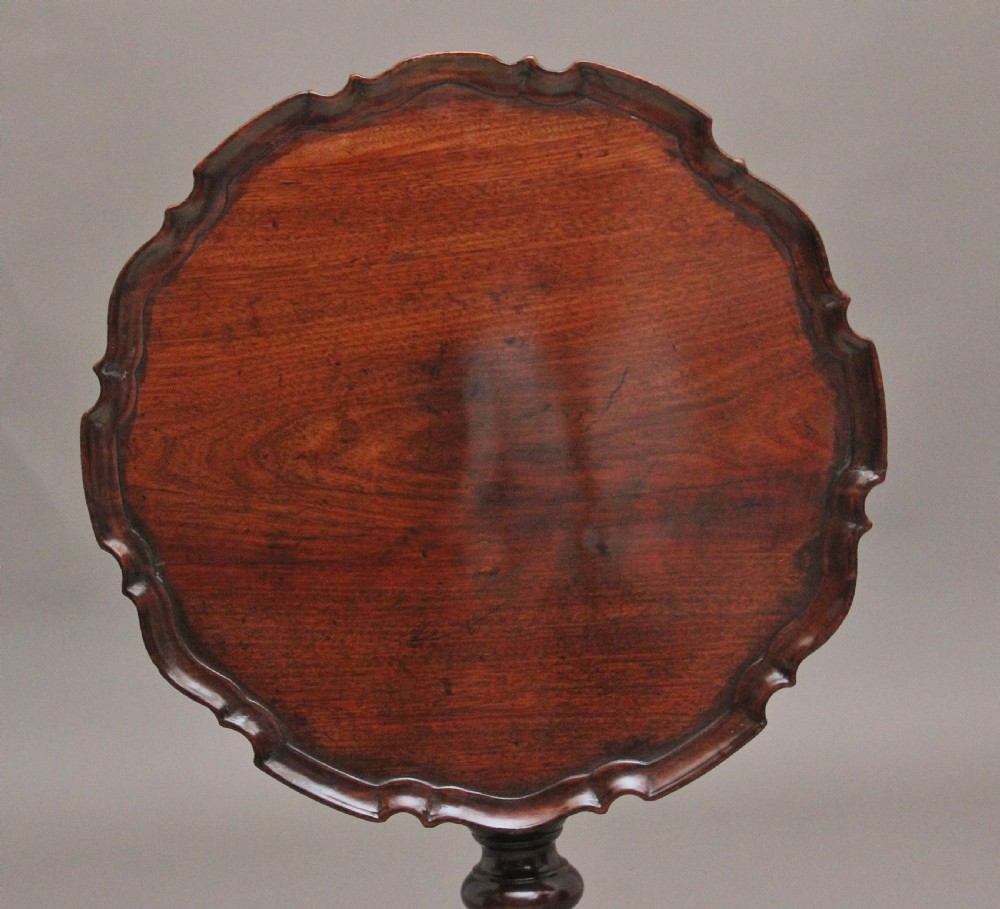 An 18th-century dark mahogany tripod table with a carved scalloped edge shown with its top tilted vertically on a turned pedestal stem. View VII