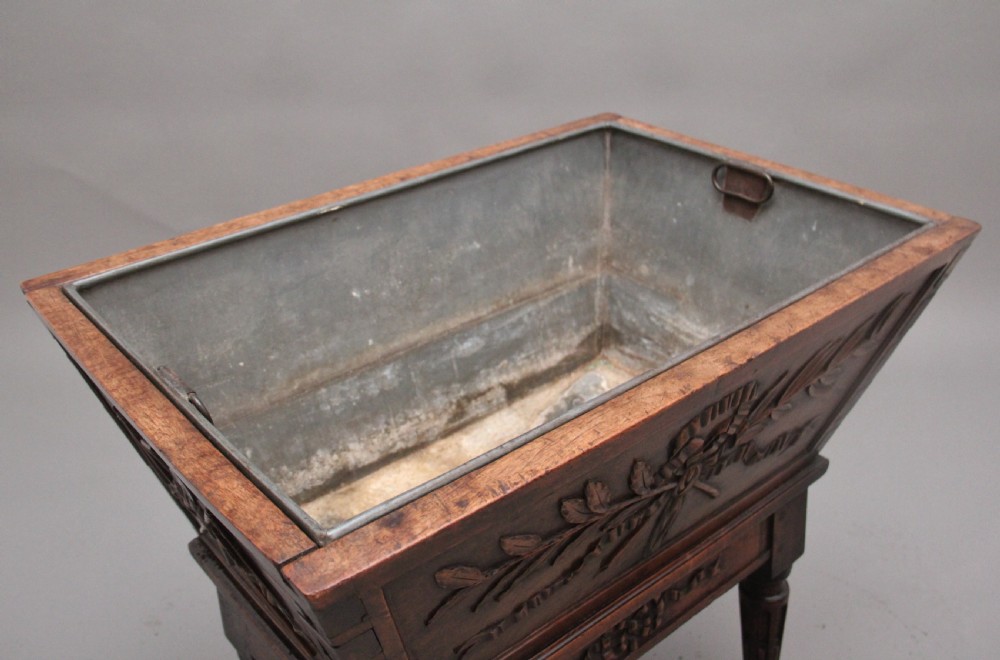 An 18th-century French carved walnut wine cooler featuring a zinc-lined tapered basin set on a stand with fluted legs and ribbon relief carvings. View III