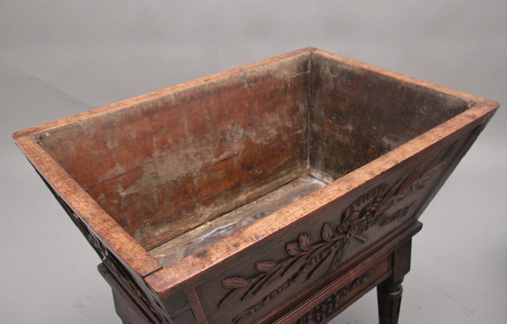 An 18th-century French carved walnut wine cooler featuring a zinc-lined tapered basin set on a stand with fluted legs and ribbon relief carvings. View IV