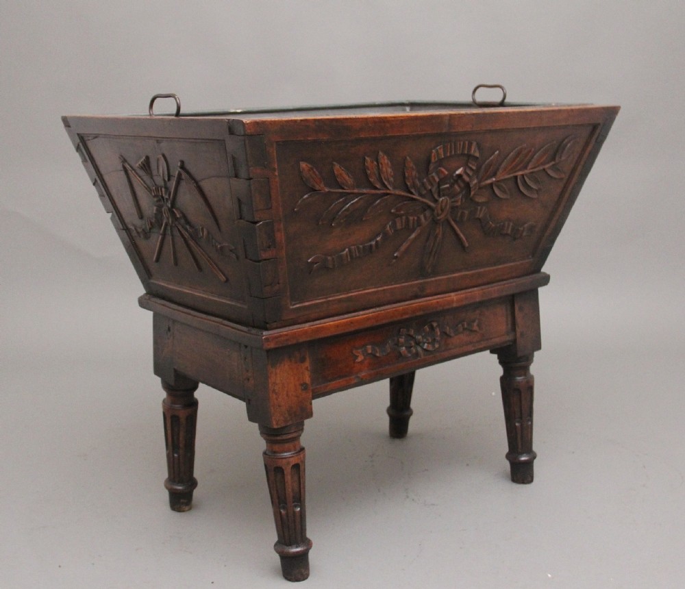 An 18th-century French carved walnut wine cooler featuring a zinc-lined tapered basin set on a stand with fluted legs and ribbon relief carvings. View VII