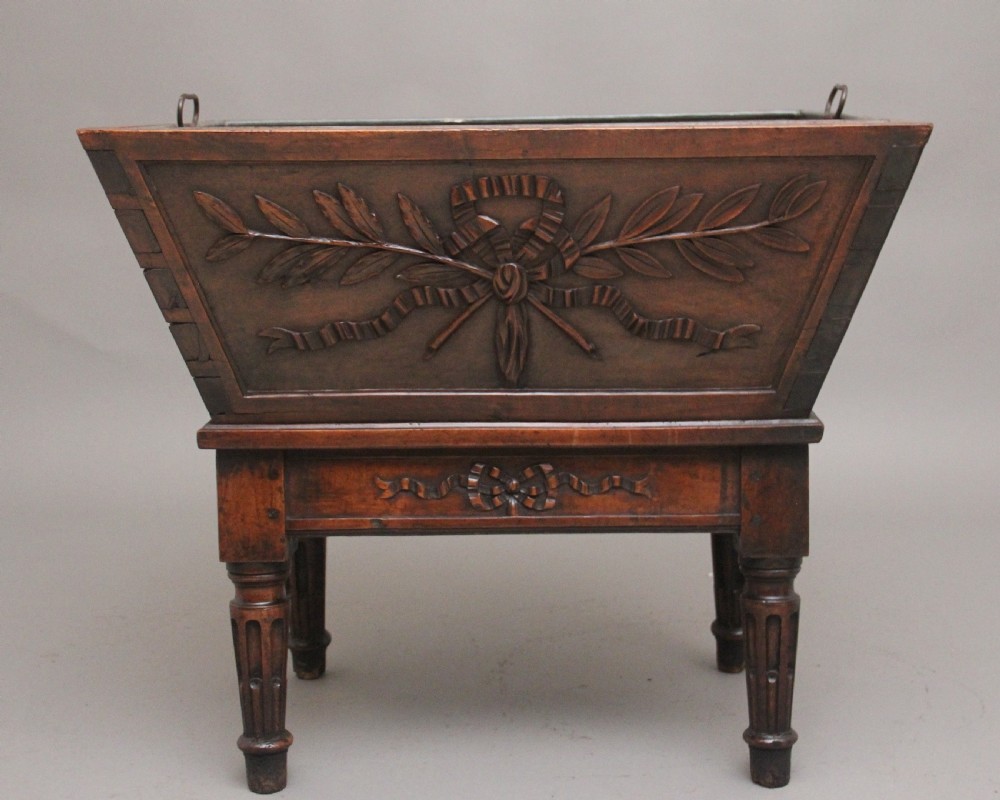 An 18th-century French carved walnut wine cooler featuring a zinc-lined tapered basin set on a stand with fluted legs and ribbon relief carvings. View VIII