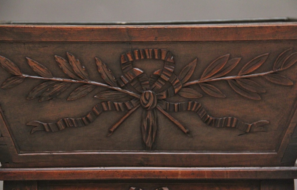 An 18th-century French carved walnut wine cooler featuring a zinc-lined tapered basin set on a stand with fluted legs and ribbon relief carvings. View XIV