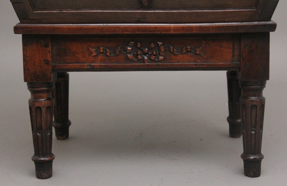 An 18th-century French carved walnut wine cooler featuring a zinc-lined tapered basin set on a stand with fluted legs and ribbon relief carvings. View XV