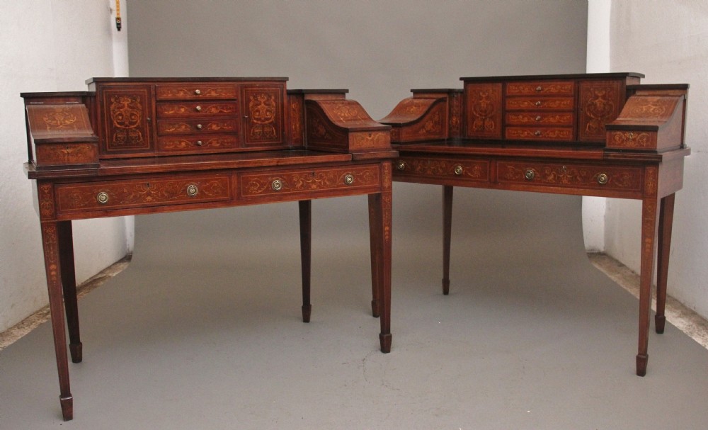 A pair of early 20th-century mahogany Carlton House desks with detailed satinwood marquetry inlay, stepped gallery drawers, and tapered legs. View II