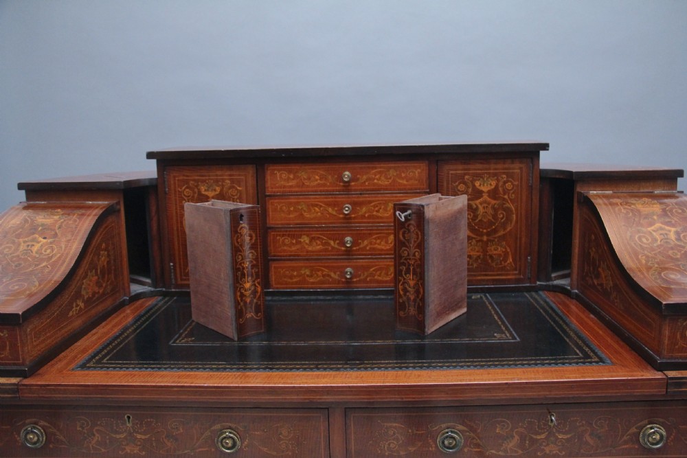 A pair of early 20th-century mahogany Carlton House desks with detailed satinwood marquetry inlay, stepped gallery drawers, and tapered legs. View XIII