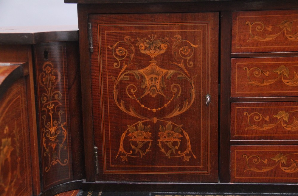 A pair of early 20th-century mahogany Carlton House desks with detailed satinwood marquetry inlay, stepped gallery drawers, and tapered legs. View XIV