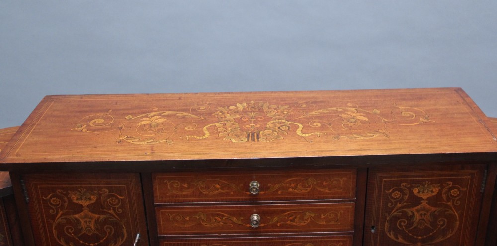 A pair of early 20th-century mahogany Carlton House desks with detailed satinwood marquetry inlay, stepped gallery drawers, and tapered legs. View XVI