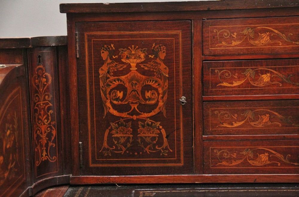 A pair of early 20th-century mahogany Carlton House desks with detailed satinwood marquetry inlay, stepped gallery drawers, and tapered legs. View XXI
